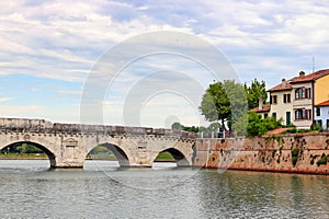 Stone Tiberius bridge and old town buildings cityscape in Rimini