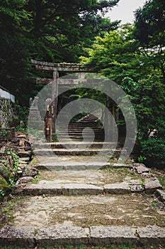 Stone torri gate over a stairs path in park on Mount Misen in Miyajima, Hiroshima, Japan