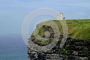 Stone tower on the green cliff against the background of a sky. Cliffs of Moher, Ireland.
