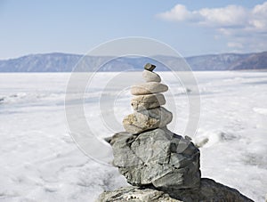 Stone tower on ice winter background. Baical landscape.