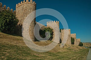 Stone towers on the large city wall and green lawn at Avila