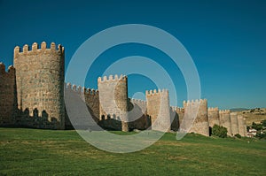 Stone towers on the large city wall and green lawn at Avila