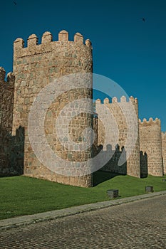 Stone towers on the large city wall next to street at Avila