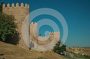 Stone towers on the large city wall next to street at Avila