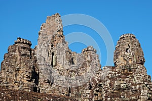 Stone towers of the medieval Khmer Bayon Temple in Cambodia against a clear blue sky