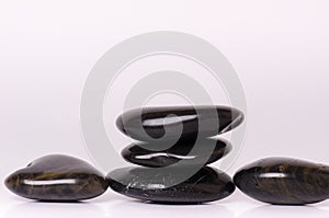 Stone treatment. Black massaging stones on a white background. Hot stones. Balance. Zen like concepts. Basalt stones.