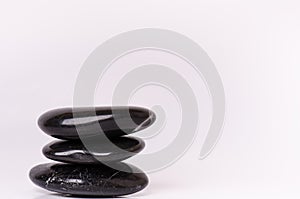 Stone treatment. Black massaging stones on a white background. Hot stones. Balance. Zen like concepts. Basalt stones.