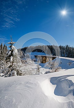 Stone viaduct arch bridge on railway through mountain snowy fir forest. Snow drifts  on wayside and hoarfrost on trees and