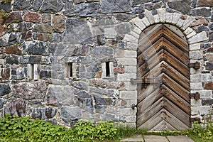 Stone wall with antique castle locked wooden door. Vintage