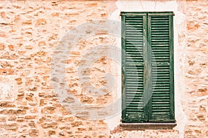 Stone wall background with old green wooden window shutters