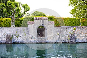 Stone wall by a canal on the background of beautiful plants in Konstanz city park, Germany