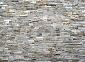 Stone wall cladding made of stacked stripes rocks. The colors are from white to gray and brown.