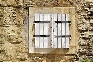 stone wall with closed wooden shutters window in Budva Old Town