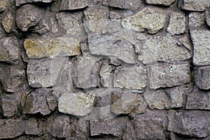 Stone wall gray cobblestone and boulders with coarse cement bonds