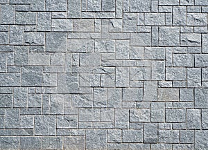 Stone wall with gray stone tiles of different dimensions and shape arranged geometrically.