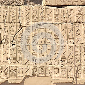 A stone wall in Karnak in Egypt with lots of hieroglyphs in the sunshine.