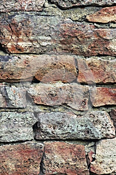 Stone wall macro closeup, stonewall pattern background, vertical, old aged weathered red and grey grunge limestone dolomite