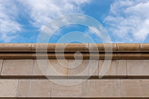 Stone wall made of dolomite against the blue sky. Rustication and cornice. Architectural detail