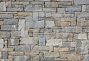 Stone wall made of irregular shaped natural rocks. The colors are gray and brown. Masonry.