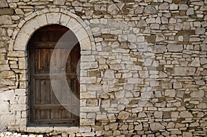 Stone wall with old wooden door in Old town Berat, Albania