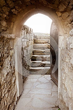 Stone wall with open door and rays of light behind