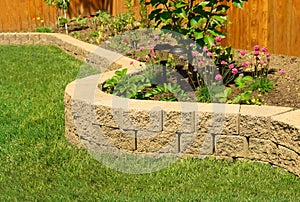 Stone wall with perfect grass landscaping in garden with artificial grass