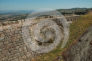 Stone wall in rocky courtyard with flowered lawn