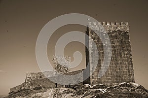 Stone wall and square tower from castle over rocky hill