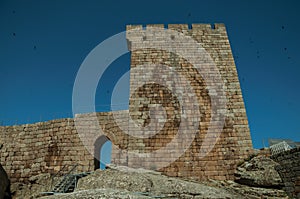 Stone wall and square tower from castle over rocky hill