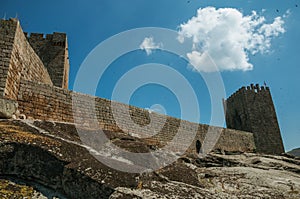 Stone wall and square tower from castle over rocky hill