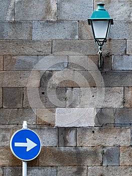 Stone wall with a street light and a traffic sign