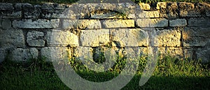 Stone Wall in Sunlight, Grassy Base, Outdoor Scene