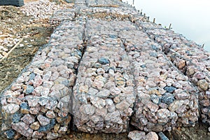 Stone walls, protection from backshore erosion. Stones in a metal mesh. Gabion wall constructed using steel wire mesh basket. Stee photo