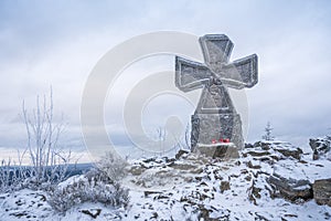 Stone war cross near Lookout tower Stepanka on the border of Krkonose and Jizera Mountains. Winter overcast day, sky