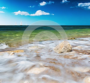 Stone washed by the waves and the boat sails on the horizon