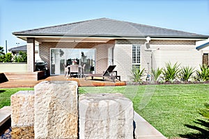 Stone water pond fixed to the lawn of a modern house with a wood