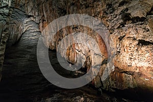 Stone waterfall rock formation and stalactites inside the cave