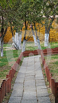 Stone way in the garden with red fence