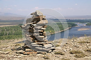 Stone zen tower at the top of a river bank