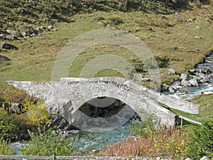 Stonebridge over a mountain river on a sunny summer day
