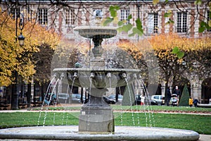 stoned fountain in vosges square in Paris by autumn