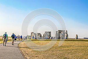 Tourists walking up path to ancient stone circle out in the middle of a plain- on hottest day in English