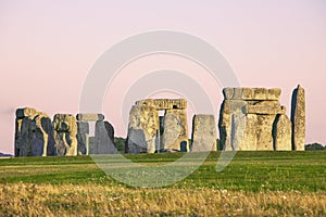 Stonehenge, warm pink sky, green summer meadow. Prehistoric monument in Wiltshire, United Kingdom. Historic Neolithic Stones.