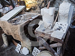 Stonemason carves and shapes the stone with a wooden hammer and chisel