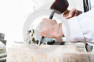 Stonemason cutting boulder with hammer and chisel