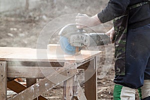 Stonemason cutting brick with diamond saw outdoors in a cloud of dust