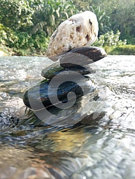 Stones are arranged in the river amidst the swift current of the river and to his surprise, this stone remains solid. photo