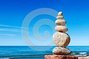 Stones balance on a background of blue sky and sea