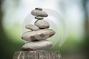 stones balance on wooden fence on green blurred backg