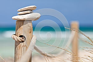 Stones balanced on wooden banister near the beach.